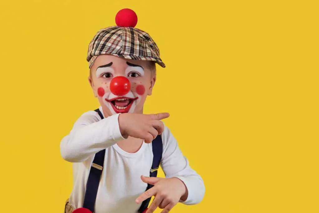 Child clown costume, yellow background. Red nose. 