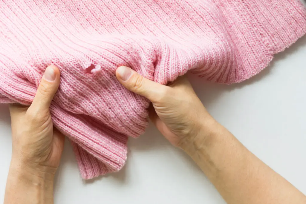hole in pink item of clothing. Pink knitted jumper.