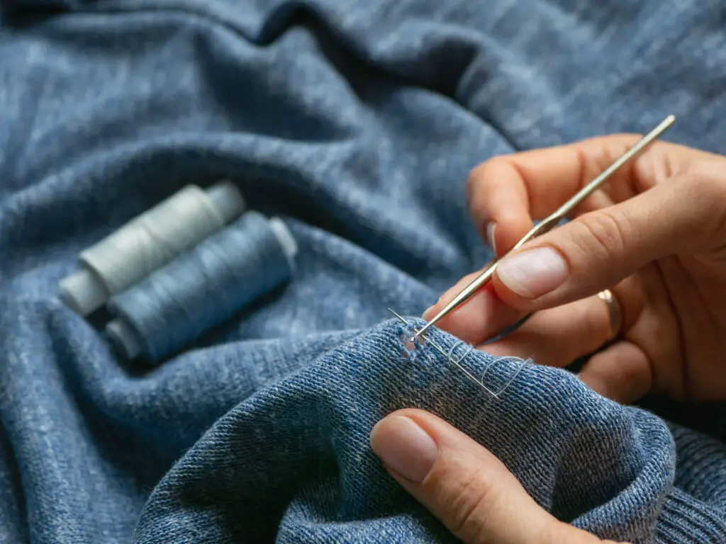 reparing a hole on a blue knitted jumper