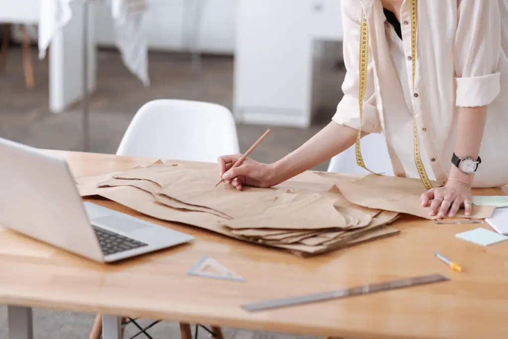 Someone in a white shirt working with a sewing pattern. 