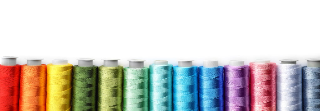 various Coloured sewing threads on white background